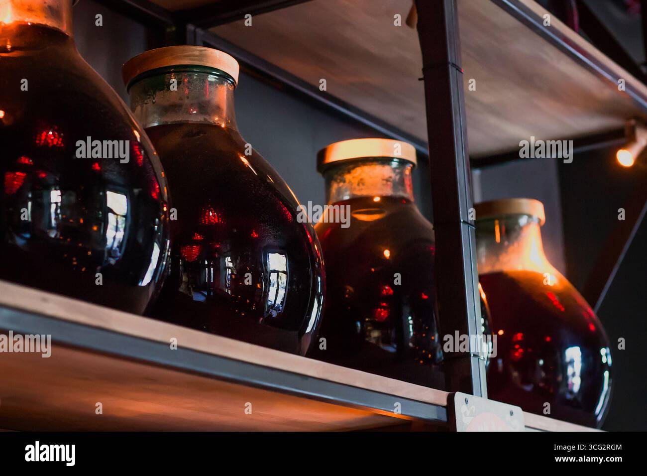 Gläser mit einem Deckel mit Rotwein werden im Keller gelagert, hausgemachter Wein befindet sich auf einem Holzregal Stockfoto
