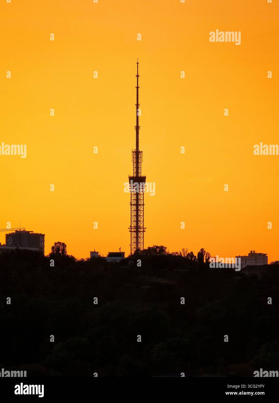 Fernsehturm bei Sonnenuntergang. Städtische Skyline mit Antennenturm gegen orangefarbenen Himmel. Stockfoto