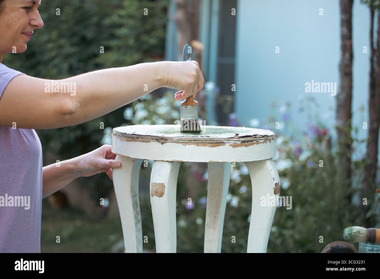 Frau mittleren Alters, die Holzmöbel anstrich. Alte Holzmöbel werden mit brandneuer, farbenfroher Kreidefarbe erneuert. Die Innendekoration wird neu gestaltet Stockfoto