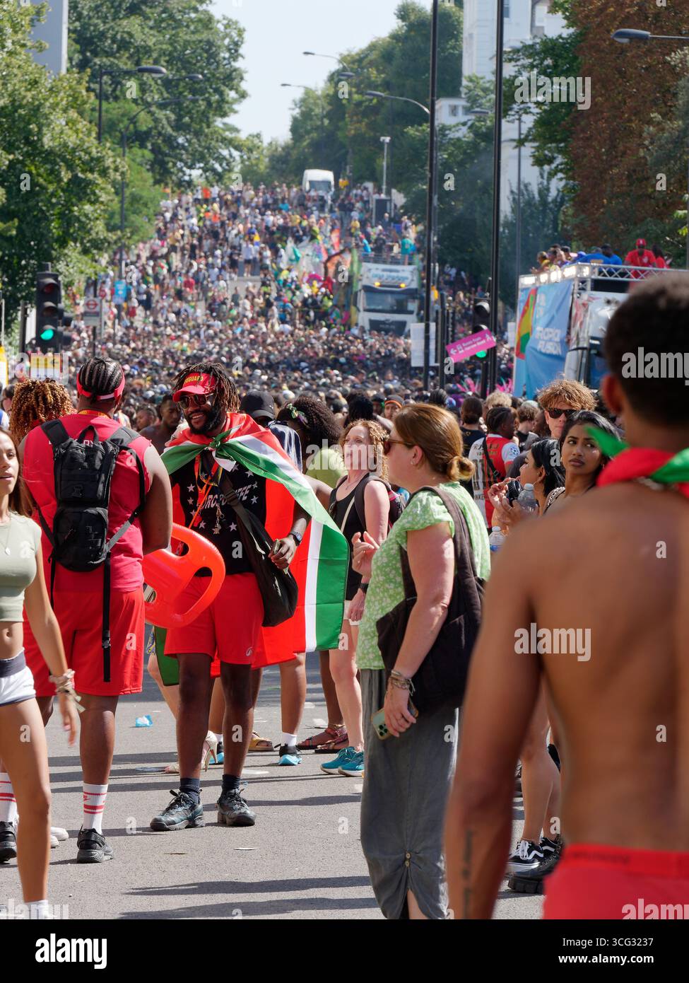 Während des Notting Hill Carnival in London füllen sich große Menschenmassen und Wagen in hellen Kleidern durch die Straßen. England, 25. August 2025 Stockfoto