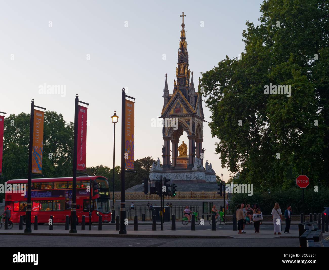 Albert Memorial an einem Sommerabend, wenn ein roter Bus vorbeifährt und Fußgänger und Radfahrer warten, um die Straße zu überqueren. London. August 2025 Stockfoto
