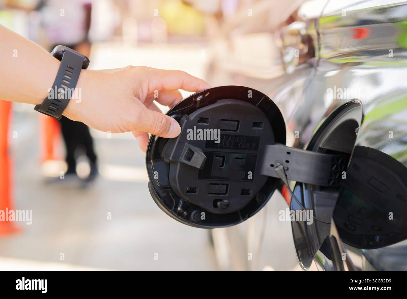 Nahaufnahme: Die Hand öffnet ein schwarzes Auto. Öffnen Sie den Benzindeckel des Fahrzeugs. Tankstellen-Konzept. Selektiver Fokus. Stockfoto