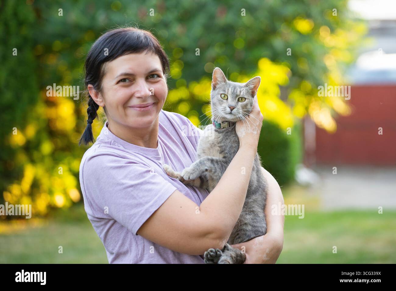 Frau mittleren Alters hält ihre süße Katze draußen. Stockfoto