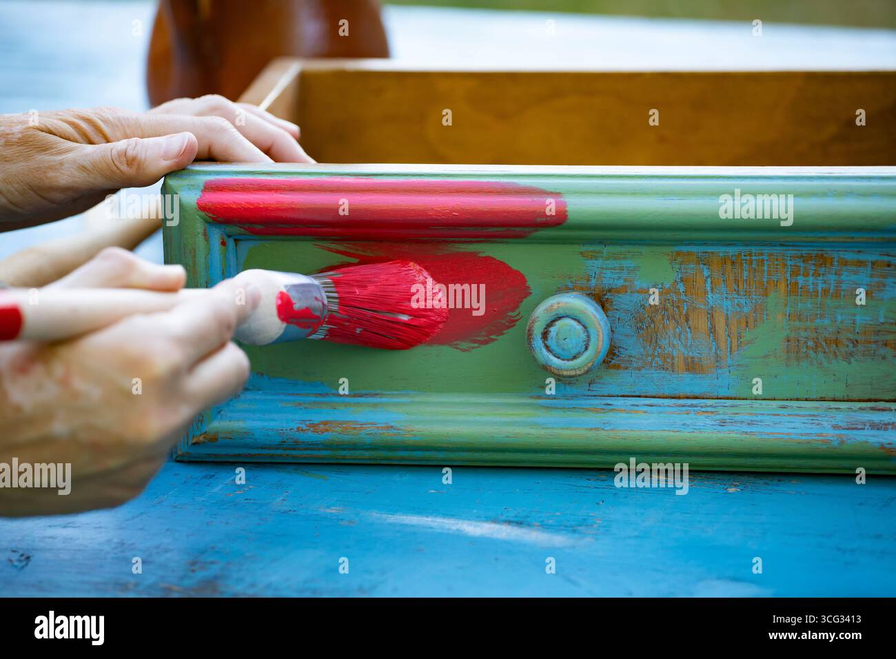 Holzmöbel mit Kreidemalerei aus menschlicher Hand. Alte Holzmöbel werden mit brandneuer, farbenfroher Kreidefarbe erneuert. Die Innendekoration wird neu gestaltet Stockfoto