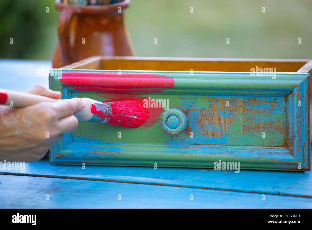 Holzmöbel mit Kreidemalerei aus menschlicher Hand. Alte Holzmöbel werden mit brandneuer, farbenfroher Kreidefarbe erneuert. Die Innendekoration wird neu gestaltet Stockfoto
