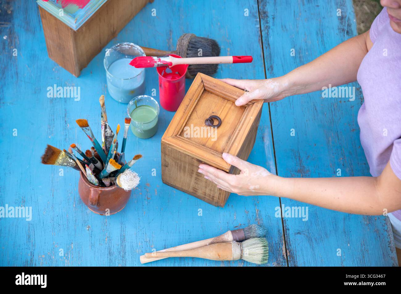 Holzmöbel mit Kreidemalerei aus menschlicher Hand. Alte Holzmöbel werden mit brandneuer, farbenfroher Kreidefarbe erneuert. Die Innendekoration wird neu gestaltet Stockfoto