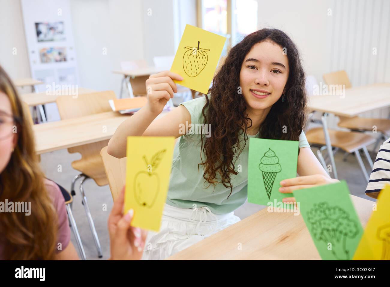 Die Schüler nehmen an einer ansprechenden Lernaktivität mit illustrierten Karteikarten teil. Im Klassenzimmer werden kollaboratives Lernen und cre betont Stockfoto