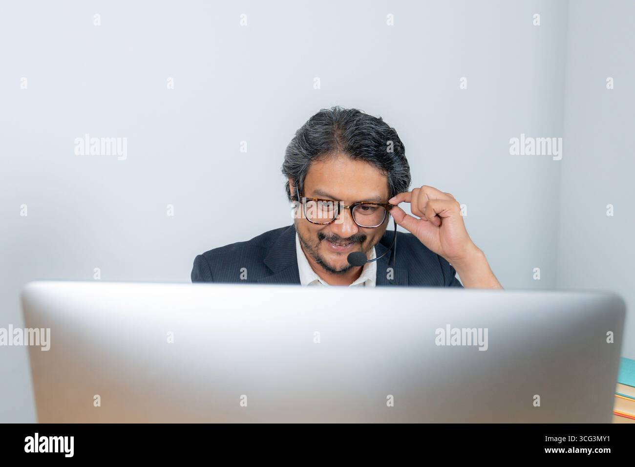 Ein junger Geschäftsmann, der an einer Online-Videokonferenz teilnimmt und für Fernarbeit, digitale Kommunikation und modernen Unternehmensstil steht Stockfoto