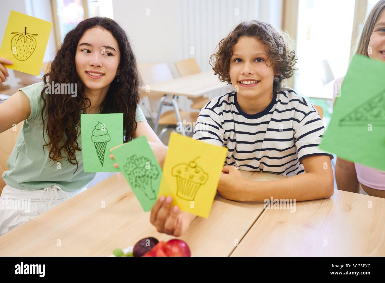Eine Gruppe verschiedener Studenten sitzt in einer Cafeteria und teilt Essensbilder und lächelt. Stockfoto
