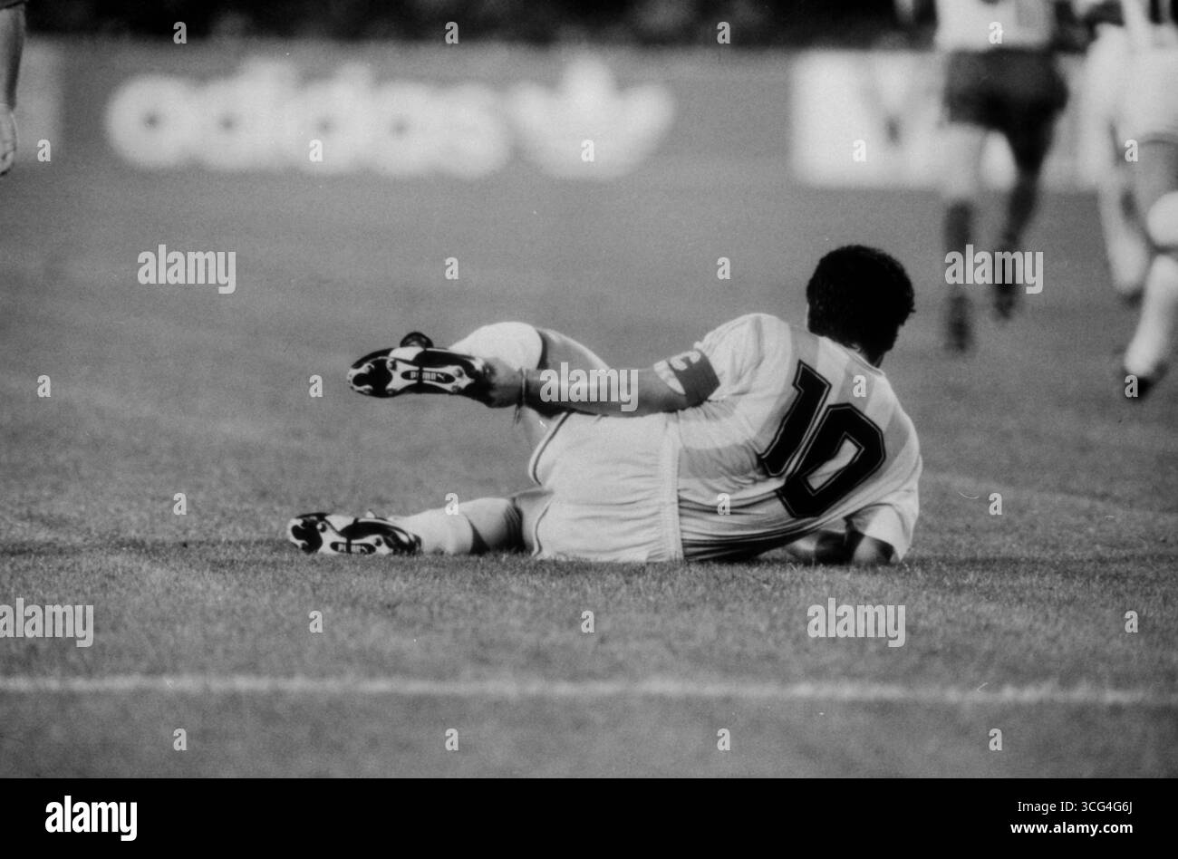 Diego Maradona liegt während des Vorrundenspiels gegen Rumänien bei der Fußball-Weltmeisterschaft 1990 verletzt am Boden und hält sich die Ferse. Stockfoto