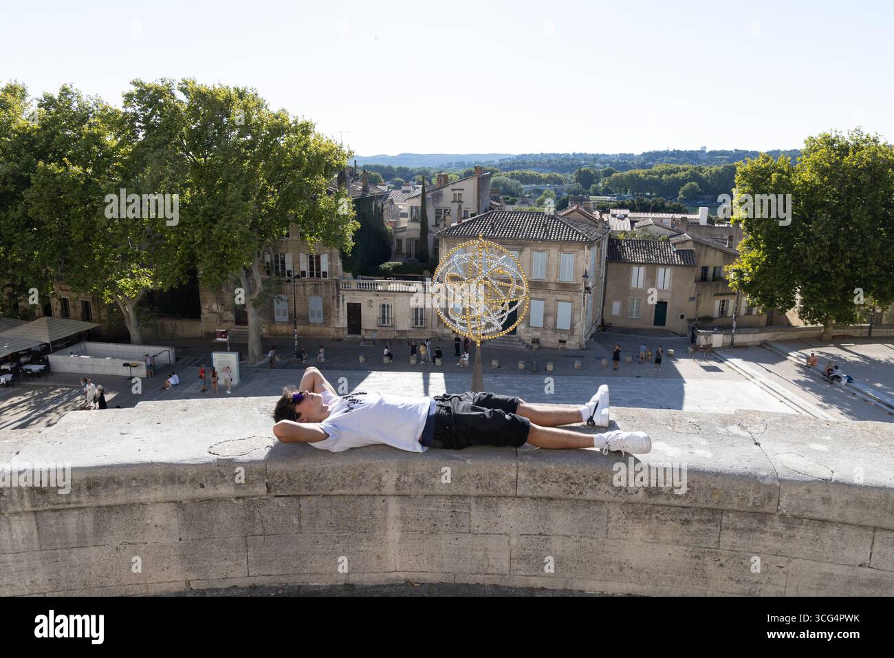 Ein Teenager, der auf einer Mauer am Place du Palais zum Palast der Päpste in Avignon, Provence, Frankreich liegt Stockfoto