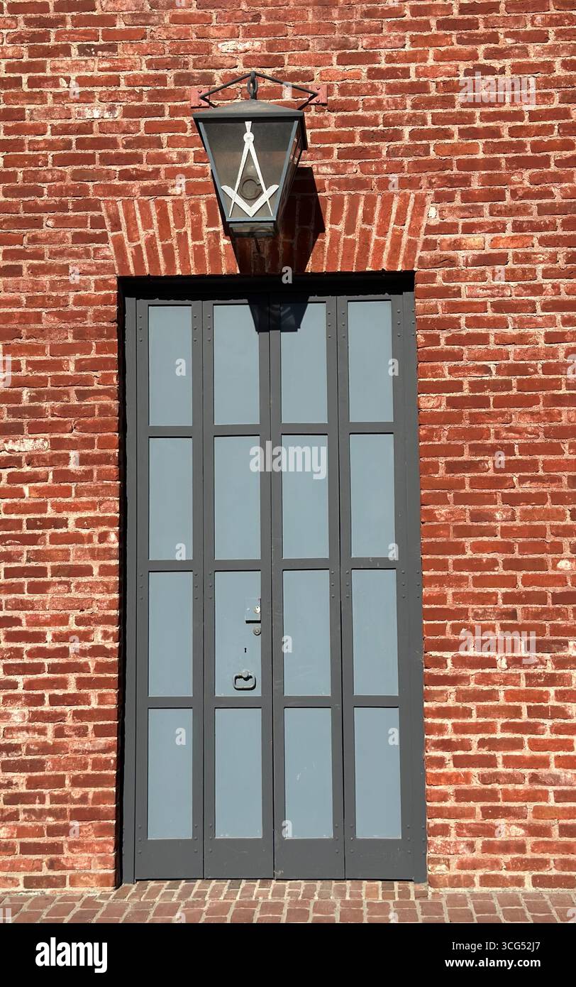 Eine Laterne mit dem Freimaurerplatz und dem Kompass-Symbol hängt außen an einem historischen Gebäude aus roten Backsteinen. - Smartphone-aufgenommenes Stockfoto