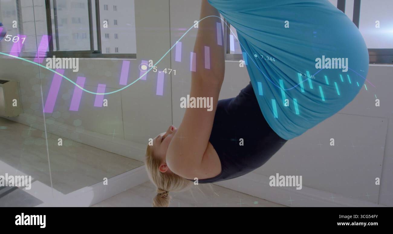 Schwangere Frau mit blaugrünen Leggings, die im Yoga-Studio Inversion macht, mit holografischen Diagrammen Stockfoto