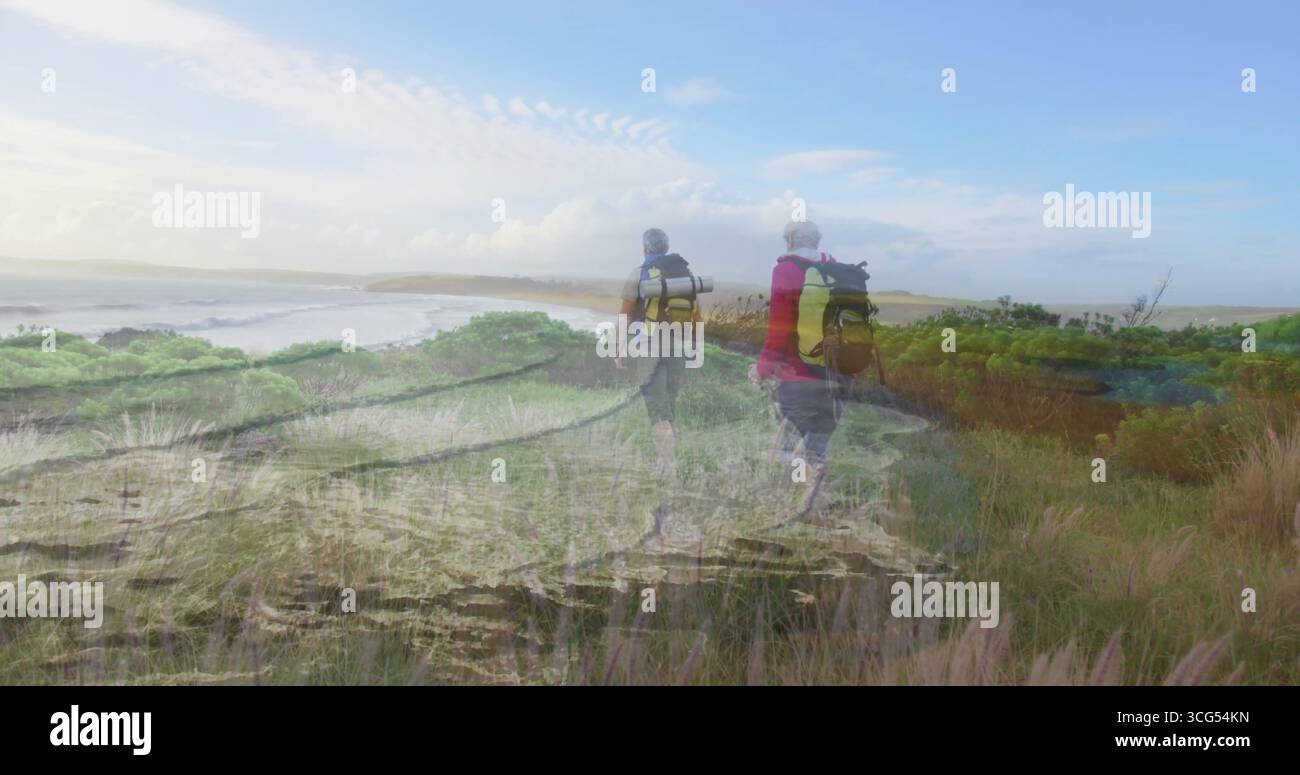 Wanderungen reifer Wanderer, die den Küstenpfad in grasbewachsenen Dünen erkunden, mit Rucksäcken und Wanderschuhen Stockfoto