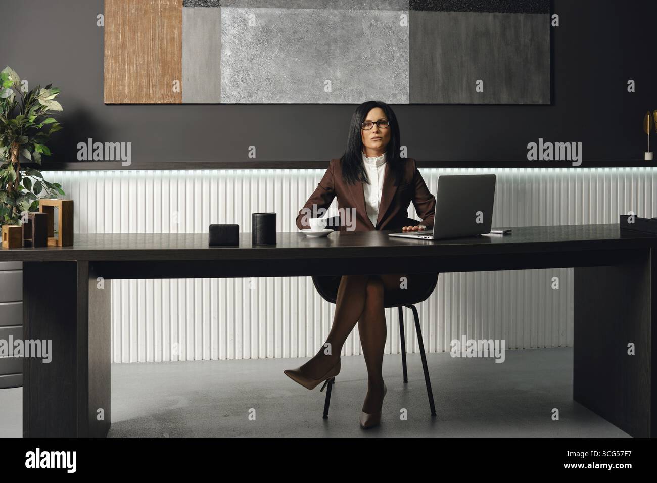 Ein professioneller Anwalt in formeller Kleidung sitzt an einem eleganten Schreibtisch in einem modernen Büro Stockfoto