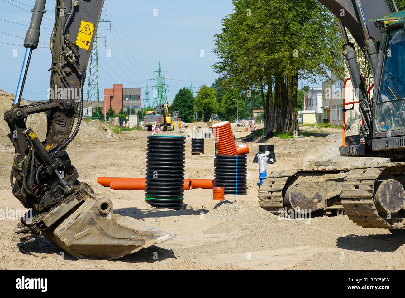 Großer Bagger auf einer Baustelle mit Entwässerungsrohren und Versorgungsinstallationen für den Ausbau der Straßeninfrastruktur Stockfoto