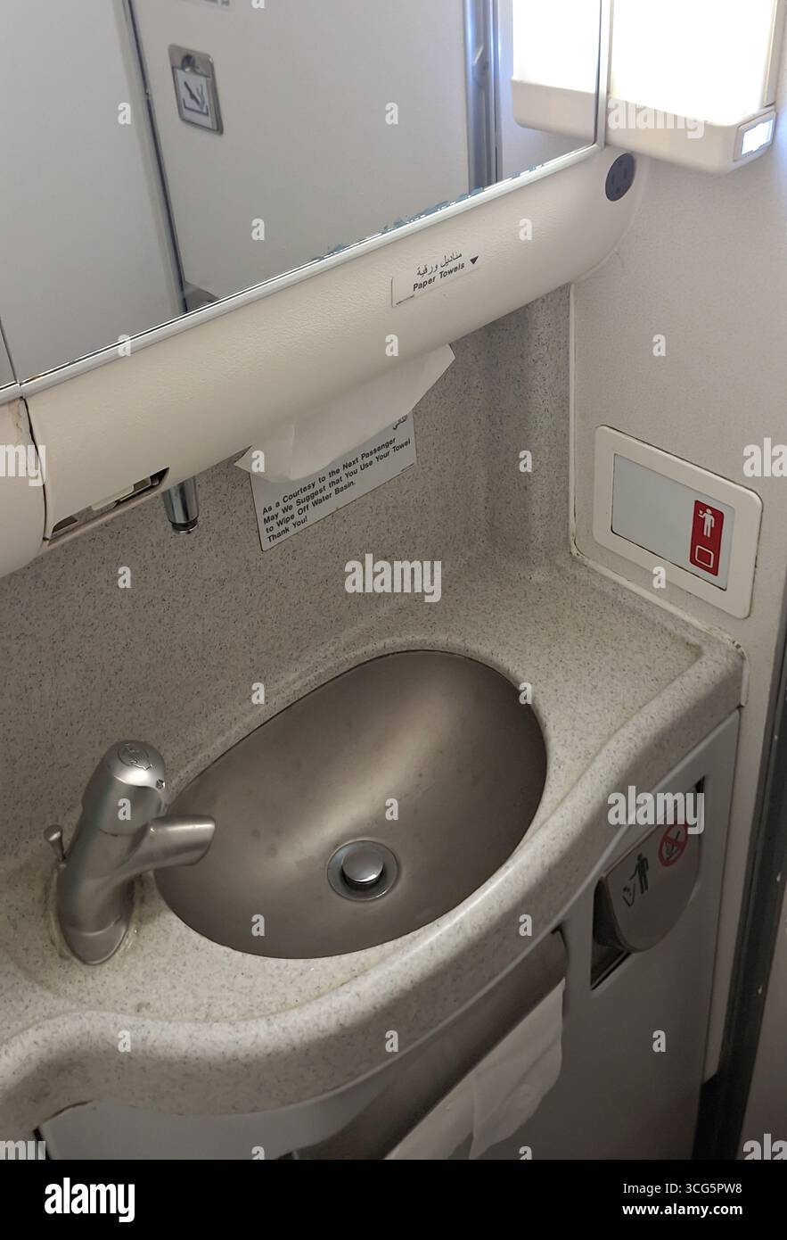 Im Inneren der Toilette des Flugzeugs ist ein elegantes Waschbecken mit einem integrierten Spiegel oben zu sehen. Schilder geben Hygieneanweisungen an, und der Raum ist sauber Stockfoto