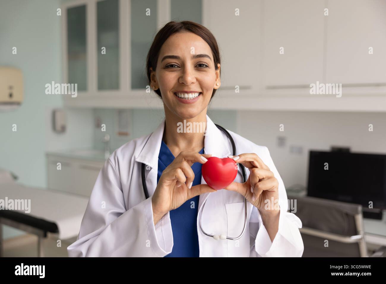 Glückliche junge Chirurgin mit rotem Herzen Stockfoto