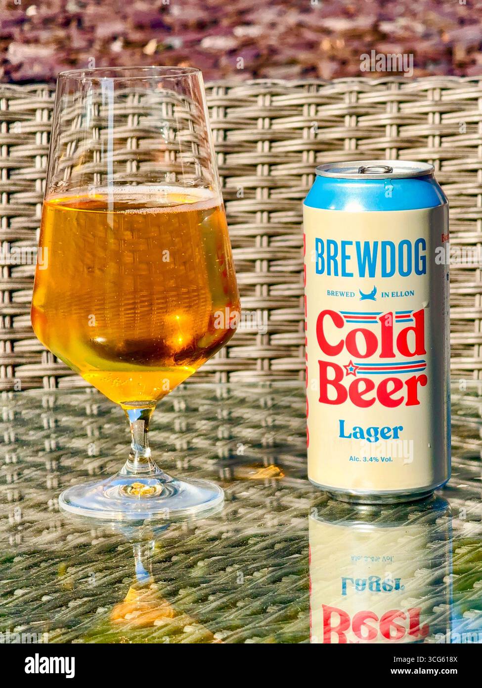Cardiff, Wales, Großbritannien - 10. August 2025: Offene Dose BrewDog Cold Beer und ein Glas Bier auf einem Tisch im Garten - Smartphone-aufgenommenes Stockfoto