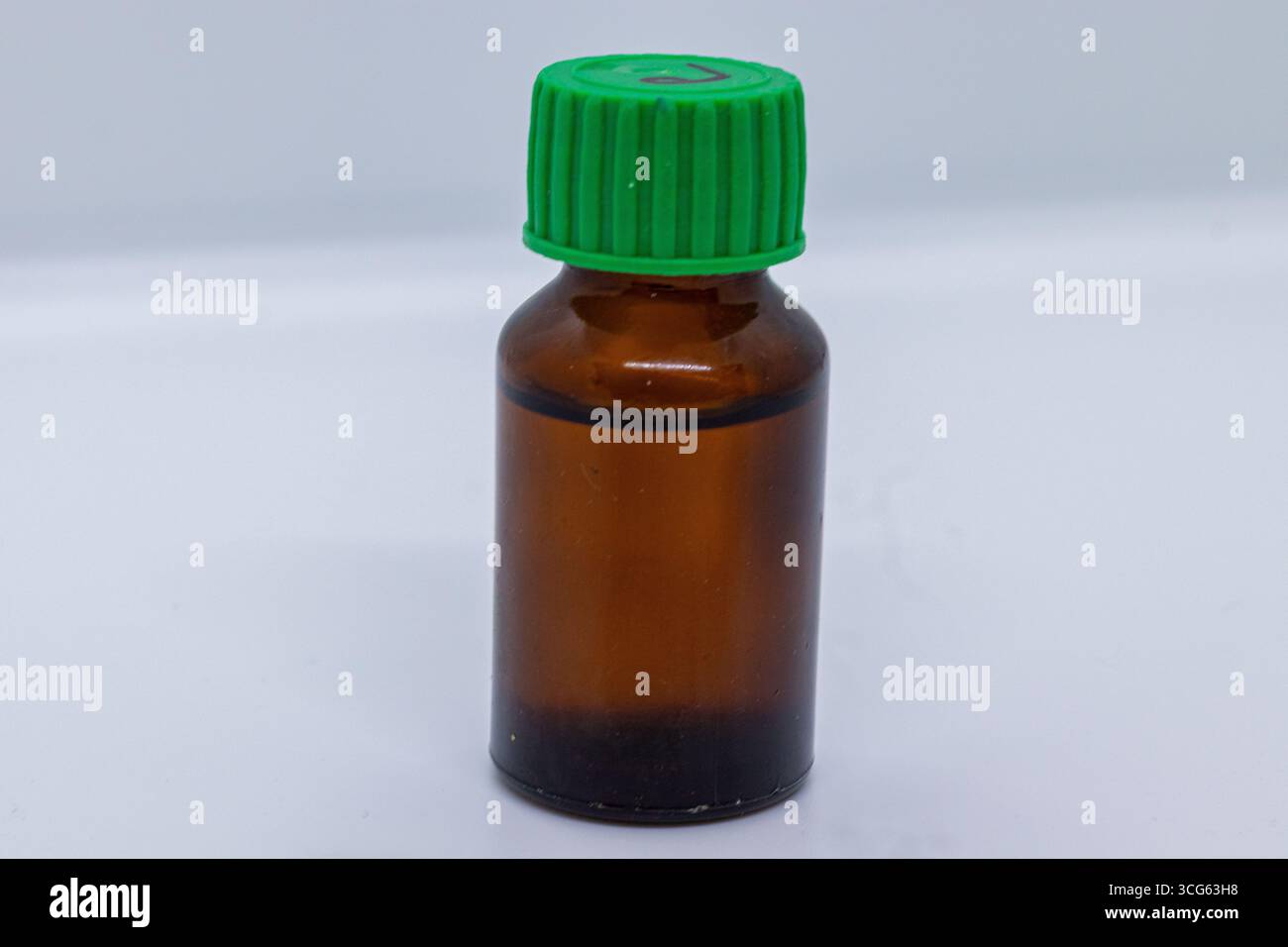 Braunglasflasche mit grünem Verschluss, ideal zur Aufbewahrung ätherischer Öle, Medikamente oder Flüssigkeiten. Isoliert auf weißem Hintergrund. Stockfoto