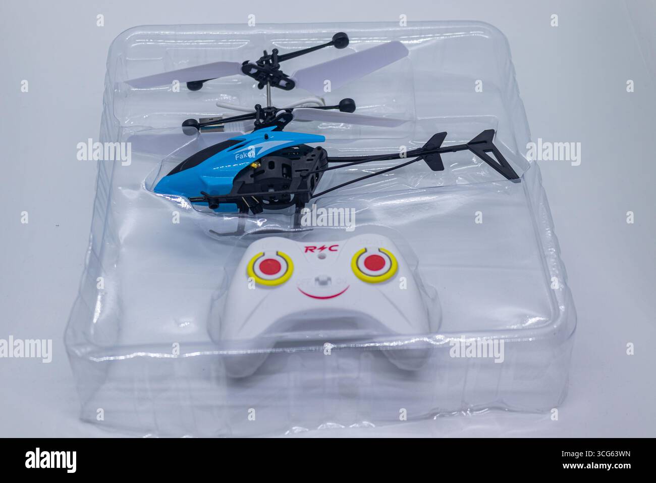 Heller blauer ferngesteuerter Spielzeug-Hubschrauber in klarer Kunststoffverpackung auf weißem Hintergrund. Stockfoto