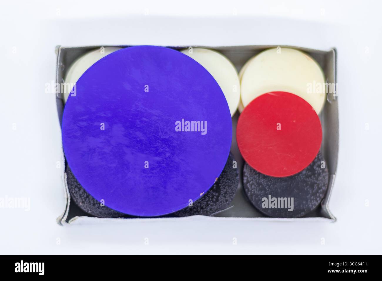 Nahaufnahme eines kompletten Carrom-Board-Münzsets isoliert auf einem sauberen weißen Hintergrund. Traditionelle Spielsteine auf der Tischplatte in leuchtenden Farben. Stockfoto