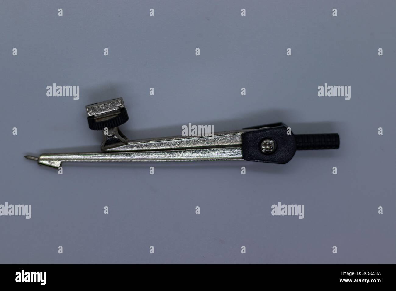 Nahaufnahme eines klassischen Bleistiftkompasses auf einer sauberen weißen Oberfläche. Traditionelles Zeichnungstool, das zum Zeichnen von Kreisen und Kreisbögen in der Geometrie verwendet wird. Stockfoto