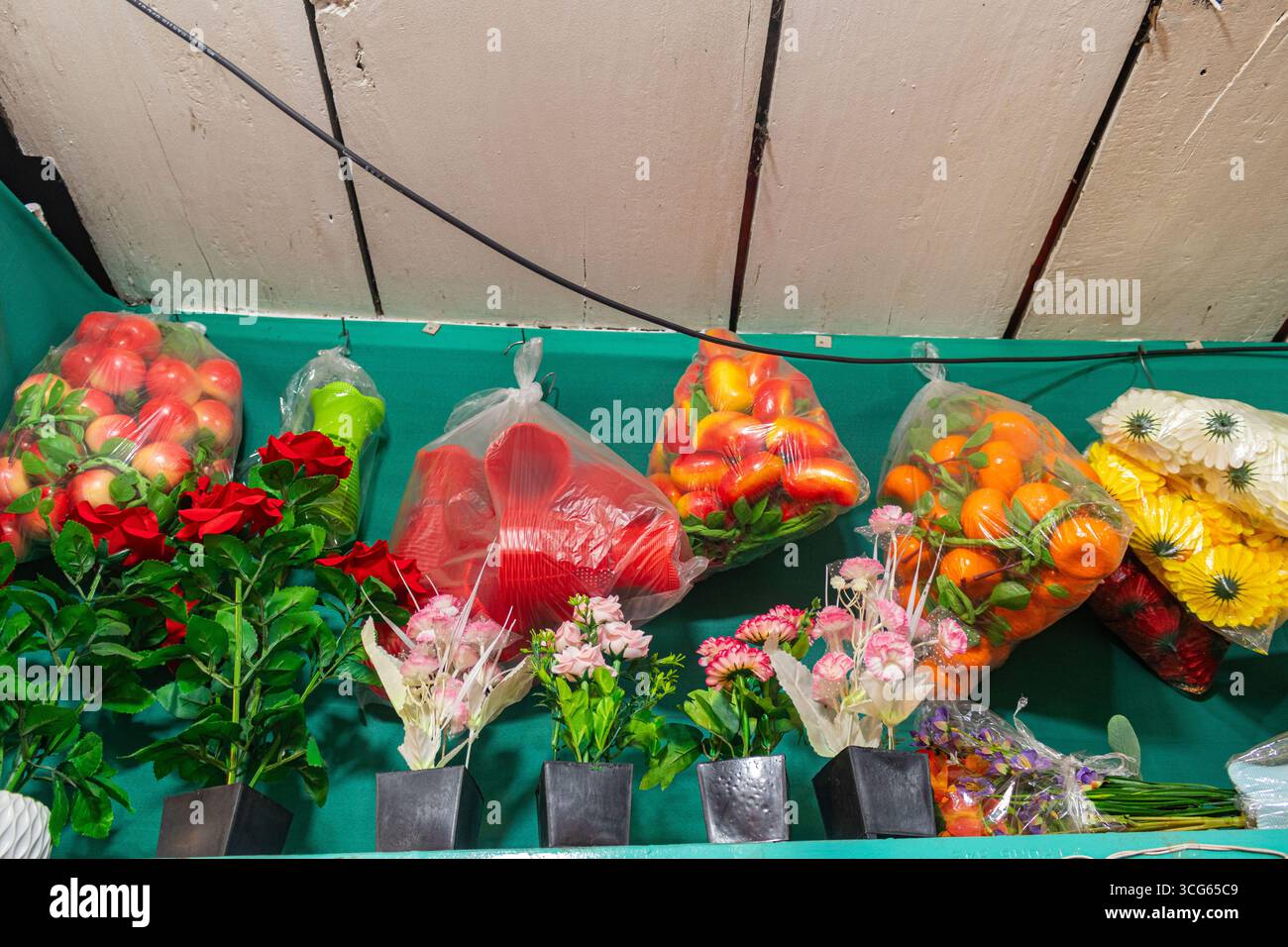 Farbenfrohe Badminton-Schläger werden neben traditioneller Hochzeitskleidung in einem lebhaften Ladeninneren ausgestellt. Eine einzigartige Kombination für Sportausrüstung Stockfoto