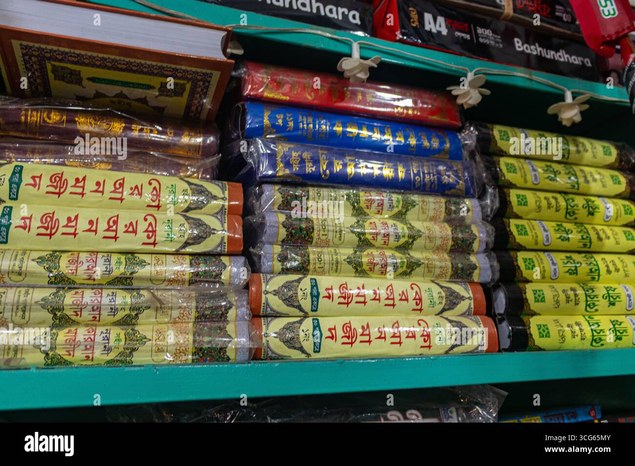 Stapel farbenfroher Koran-Sharif-Bücher mit wunderschön verzierten Covern, die auf einem Regal in einem Buchladen ausgestellt sind. Islamische religiöse Texte ordentlich angeordnet, ideal Stockfoto