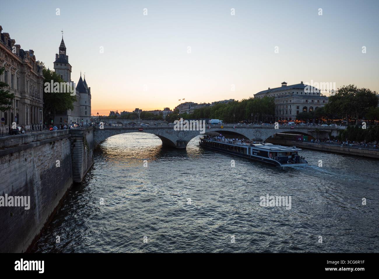 In der Abenddämmerung gleitet ein Bateaux-Mouches-Boot unter einer historischen Brücke auf der seine in Paris, Frankreich. Stockfoto