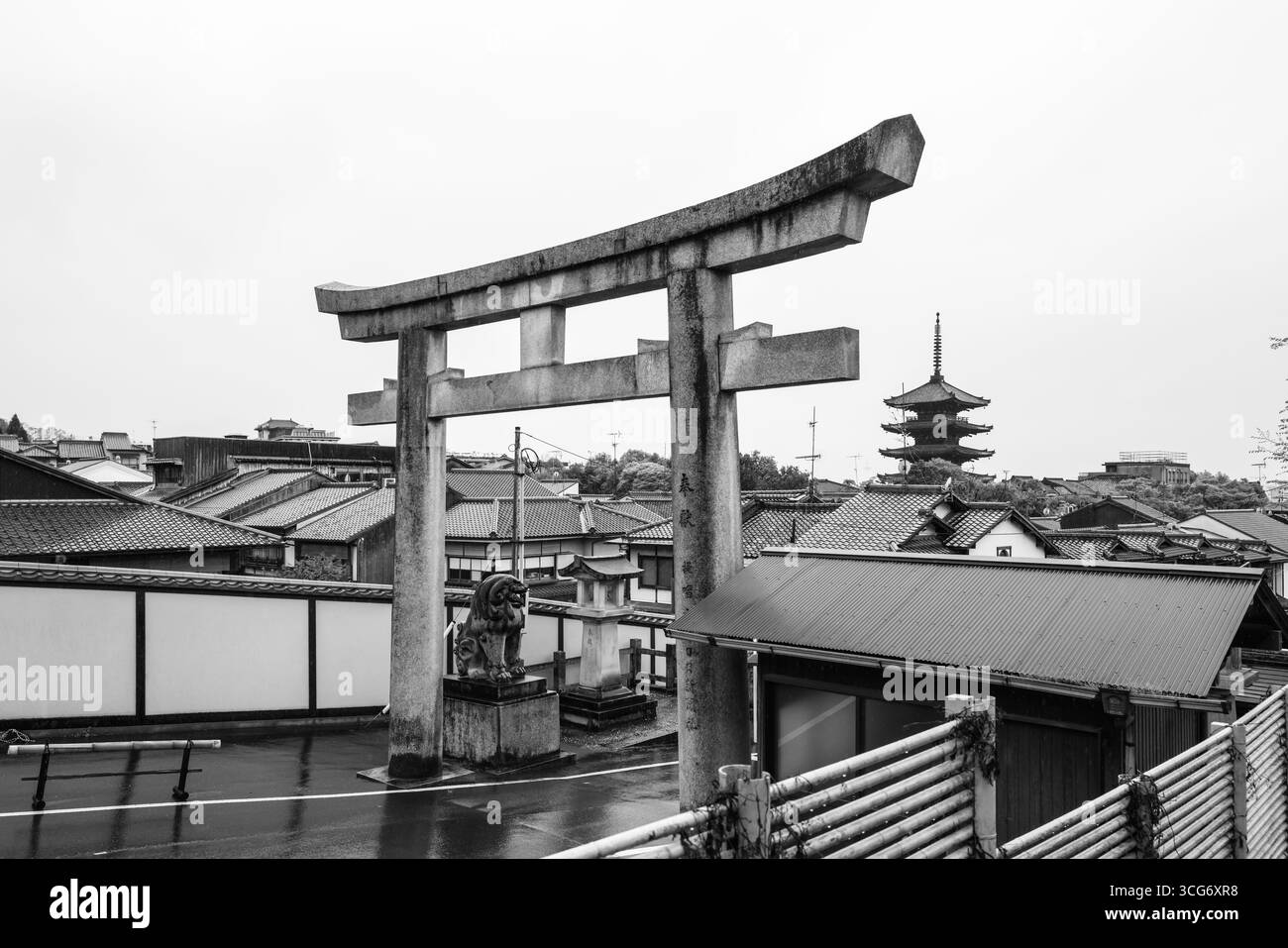 Ein Schwarzweiß-Foto des Kyoto Ryozen Gokoku-jinja Torii Tores, gesehen neben einer ruhigen Pagode. Die Szene zeigt traditionelle Architektur und Stockfoto