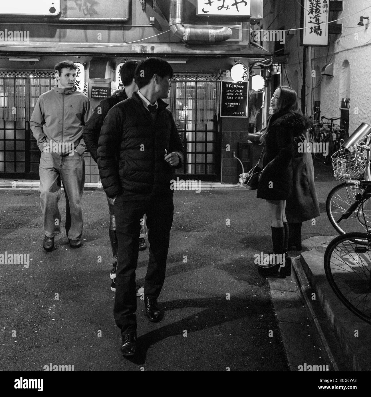 Schwarzweiß-Foto, das Menschen in einer japanischen urbanen Umgebung zeigt, lokale Einrichtungen und nächtliches Ambiente zeigt, Nakagyo W Stockfoto