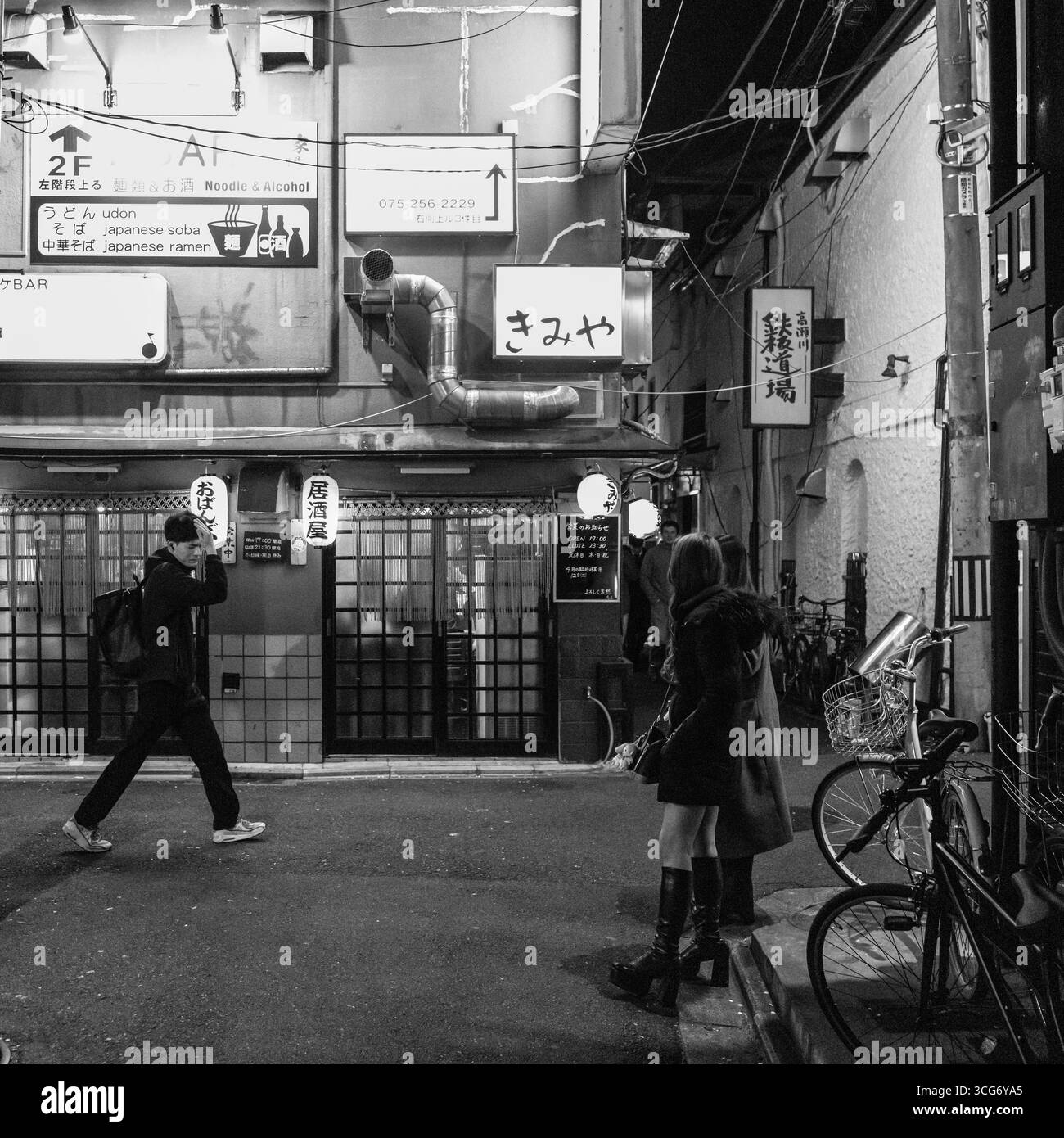 Schwarzweiß-Foto einer Kyoto-Straße mit Geschäften, Menschen in Bewegung und stimmungsvoller Beleuchtung, Nakagyo Ward, Kyoto, Kansai, Honshu, Japan Stockfoto