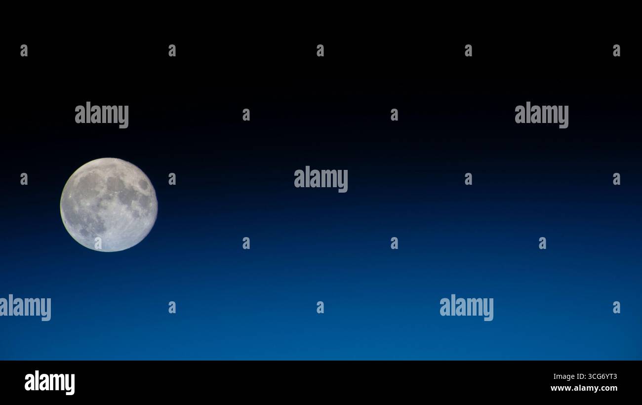 Ein Vollmond ist von der Internationalen Raumstation abgebildet. Der Mond bleibt links vom Bild, mit einem Horizont aus blauem Licht der Erde, der das Bild fast in zwei Hälften teilt und sich in das Schwarz des Weltraums einfügt. 30. September 2023 eine optimierte Version eines Originalbildes der NASA: Credit NASA Stockfoto