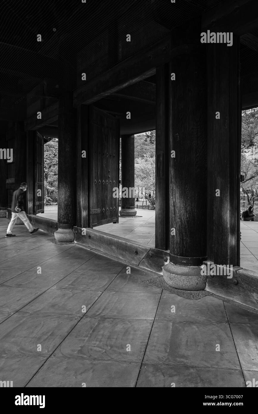 Schwarzweiß-Foto eines historischen hölzernen Sanmon-Tors, das komplexe Handwerkskunst und kulturelle Atmosphäre zeigt, mit einer Einzelfigur und surr Stockfoto