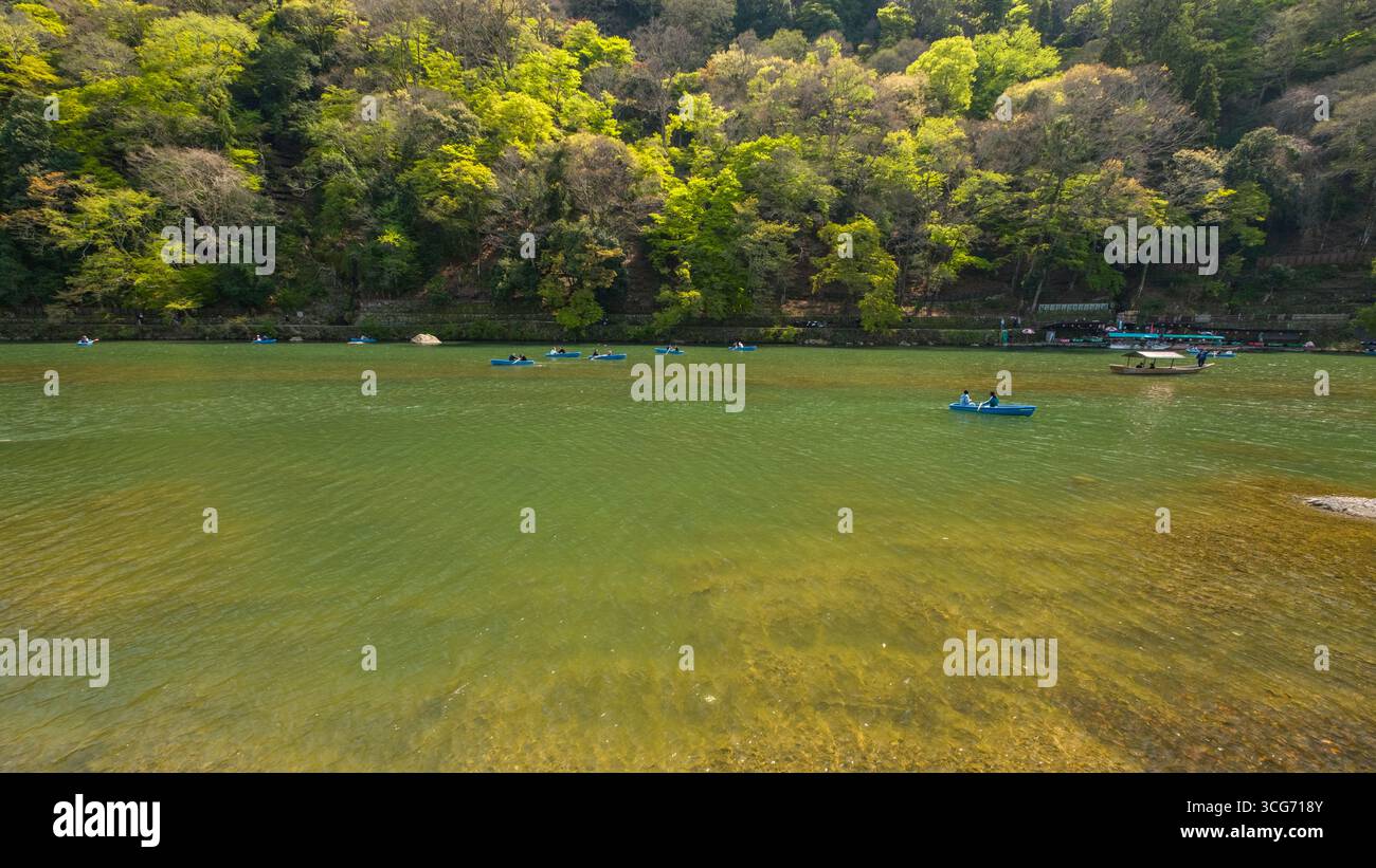 Touristen rudern kleine Ruderboote im Fluss Katsura an einem sonnigen Tag im April, Arashiyama, Ukyo Ward, Kyoto, Kansai, Honshu, Japan Stockfoto