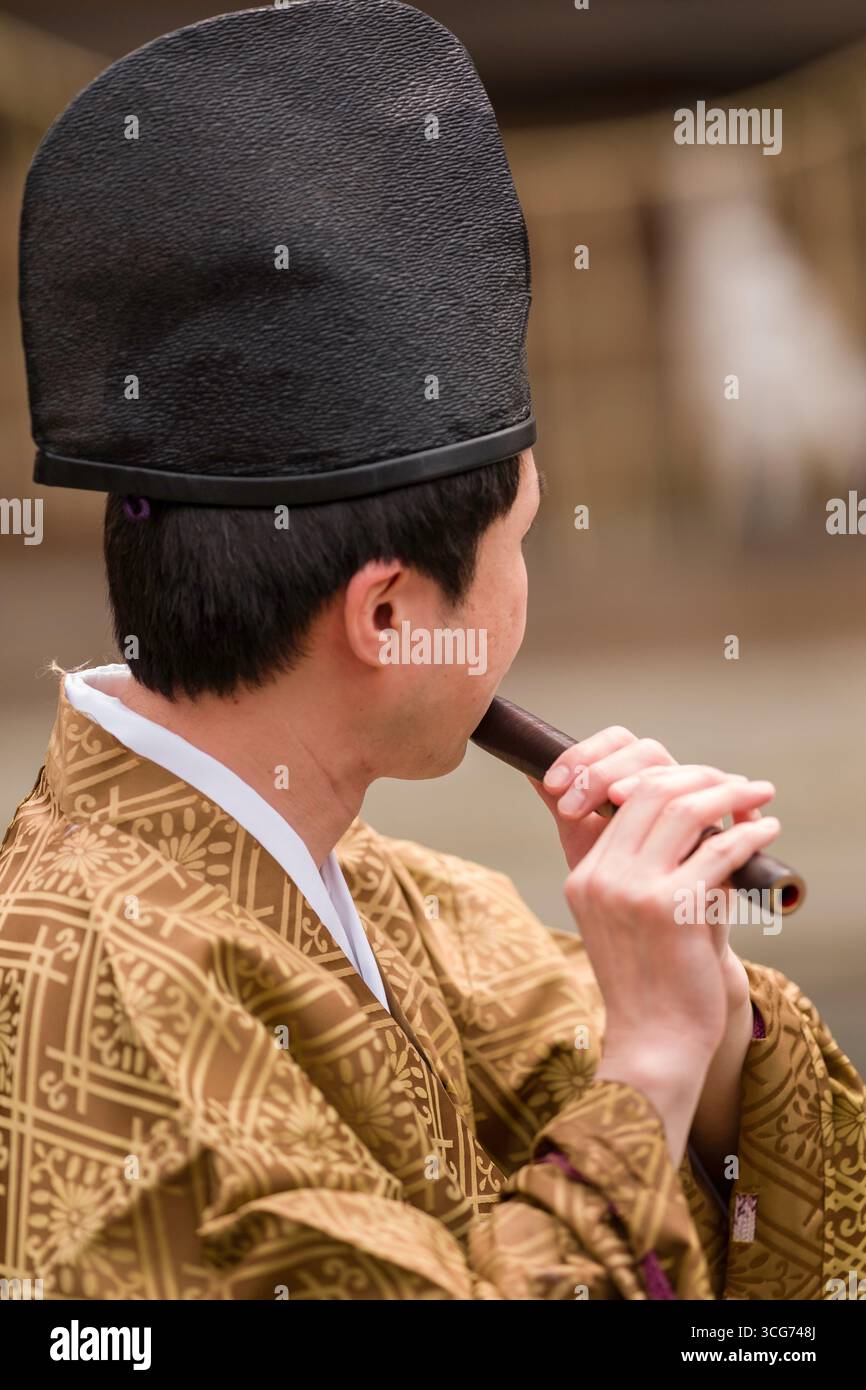 Männlicher Musiker, der traditionelle Shinto-Musik auf einer Shinobue-Flöte während des Oukasai Cherry Blossom Festivals im Hirano-Schrein in Kyoto, Japan vorführt Stockfoto