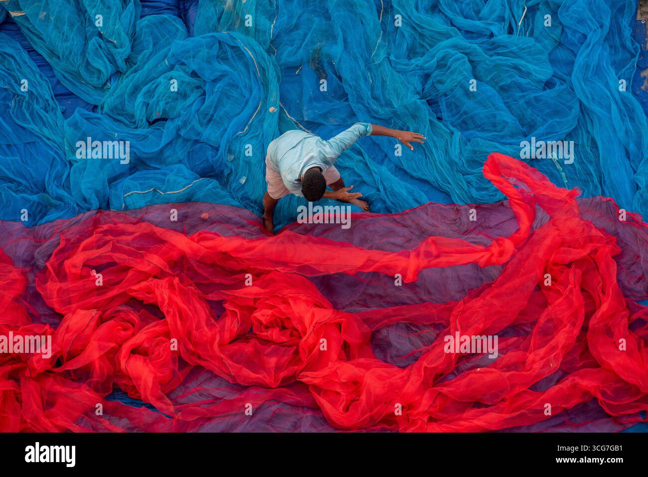 Nicht identifizierte Fischer, die bunte Fischnetze anordnen Stockfoto