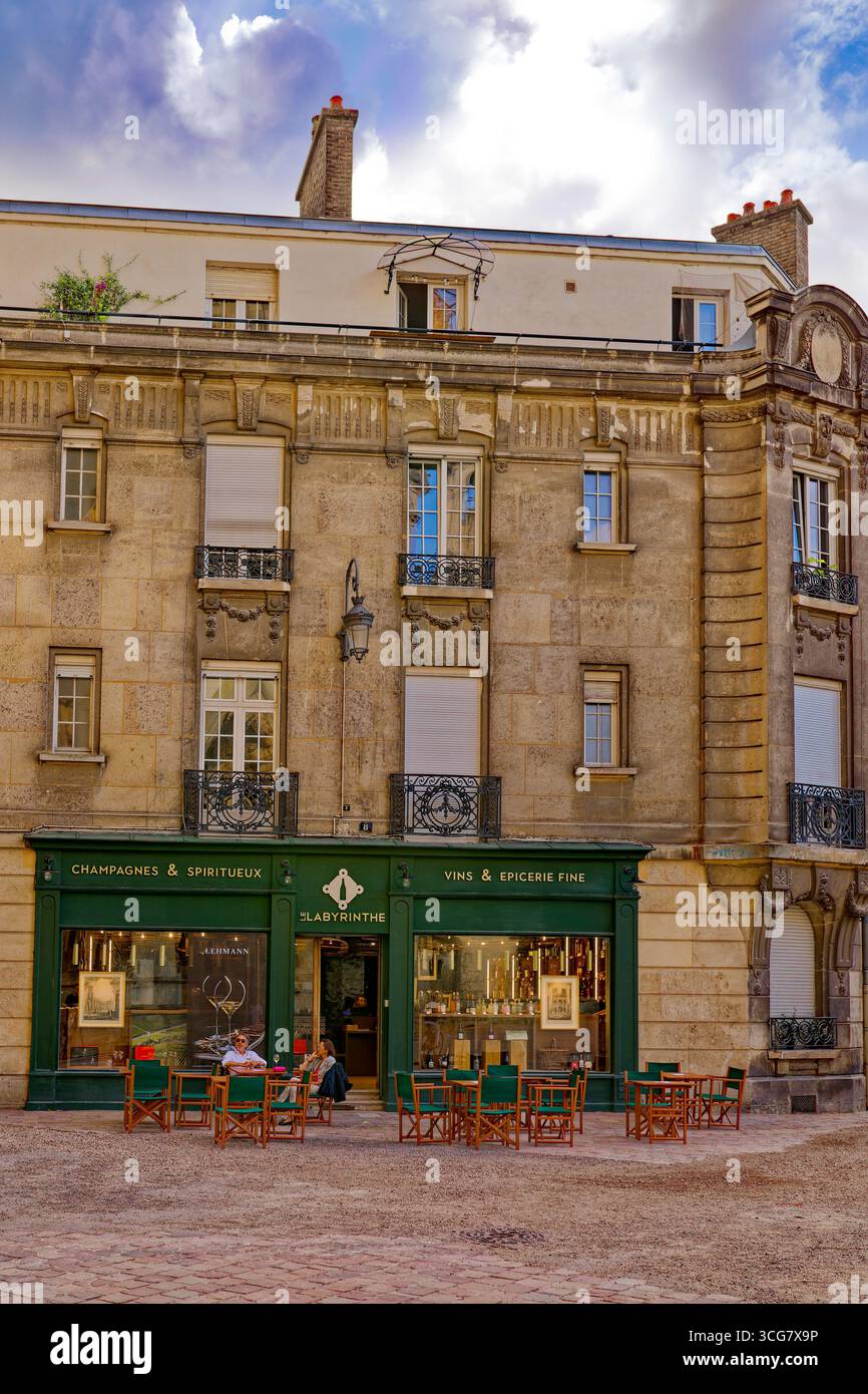 Champagner- und Weinladen mit Gästen, die unter dramatischem bewölktem Himmel im historischen Reims, Frankreich, eine Weinprobe im Freien genießen Stockfoto