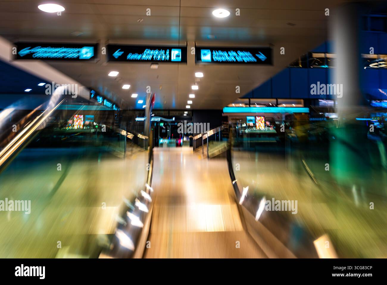 Beleuchteter Flughafen Zürich mit Eskalator in unscharfer Bewegung bei Nacht im Flughafen Kloten, Zürich, Kanton Zürich, Schweiz. Stockfoto