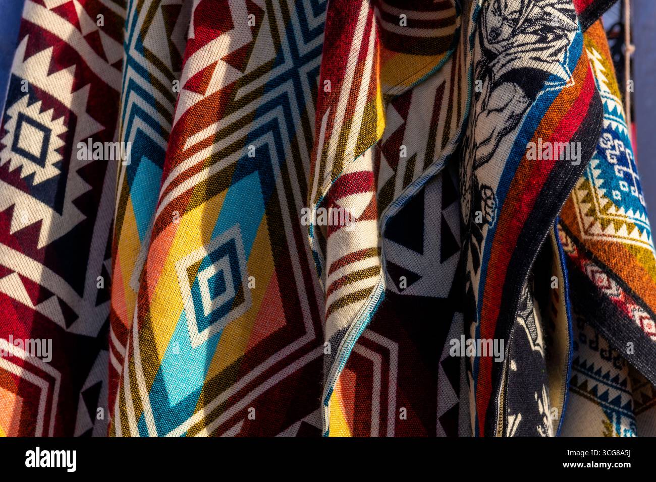 Hängende traditionelle andenponchos auf dem Kunsthandwerksmarkt in Otavalo, Ecuador. Entwürfe sind in Ecuador, Peru und Bolivien zu finden. Stockfoto