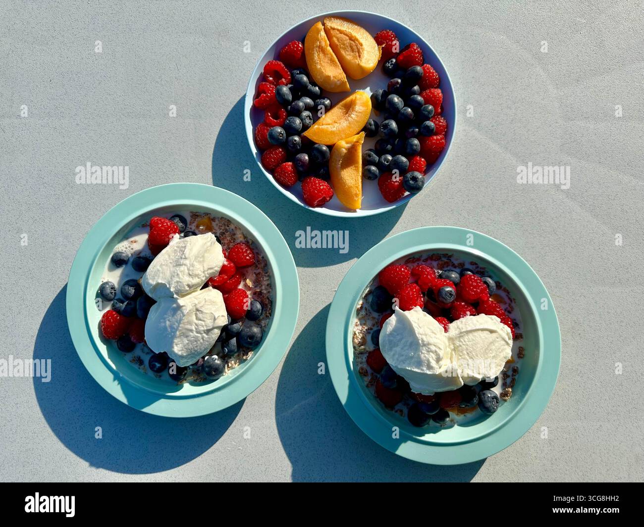 Drei Plastikteller mit Obst, Müsli, Joghurt und Müsli Stockfoto