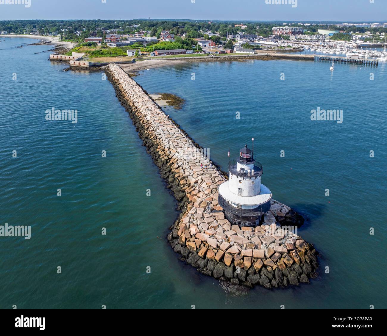 Spring Point Ledge Lighthouse steht am Ende eines langen Steinstegs, der sich in ruhiges blaues Wasser erstreckt. Die Kulisse zeigt ein hektisches Har Stockfoto