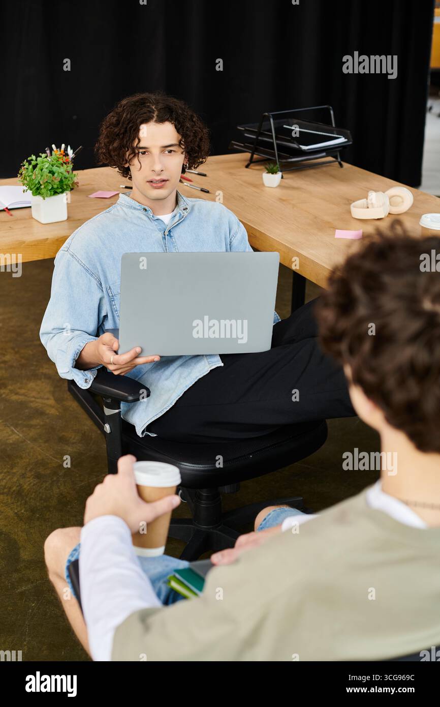 Zwei junge Fachkräfte führen während ihrer Arbeit in einem geräumigen Büro eine dynamische Diskussion. Stockfoto