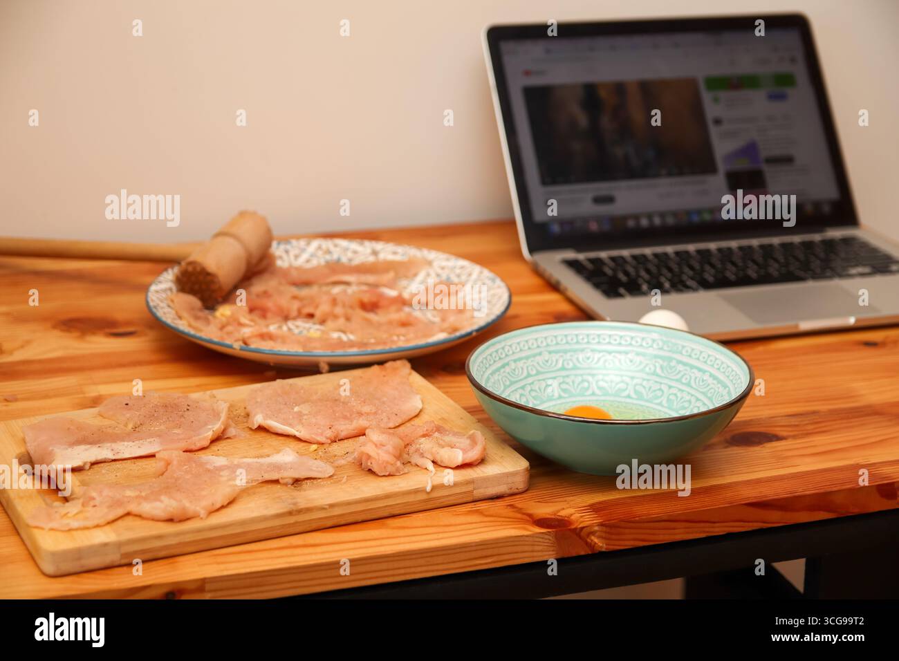 Ein schönes und elegantes Konzept einer gesunden Küche. Gesunde Mahlzeit Vorbereitung Laptop Rezept. Kochprozess von Hähnchenrezept-Laptop. Hausmannskost Stockfoto