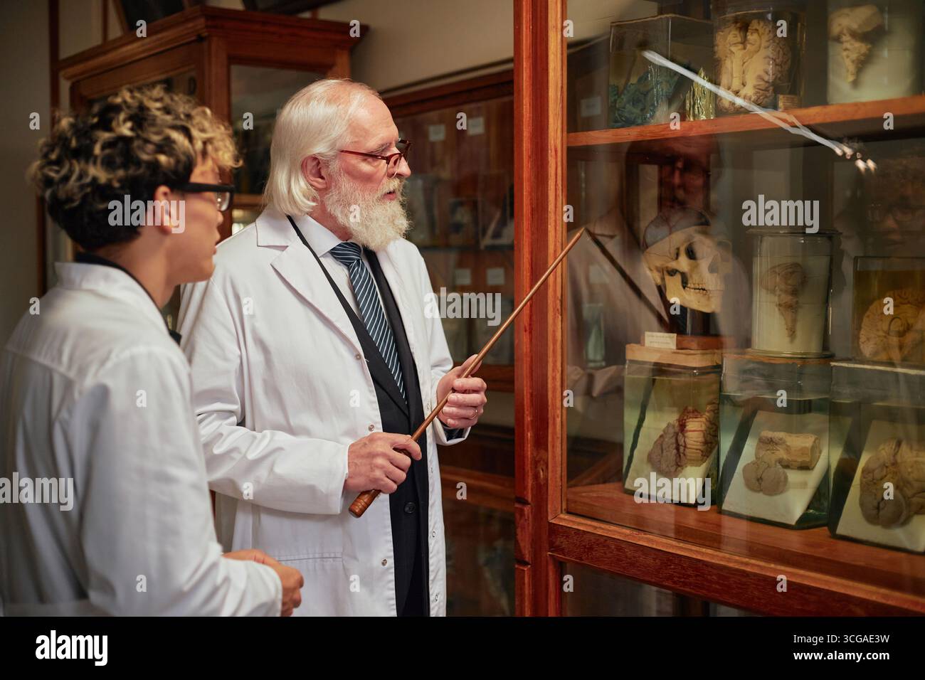 Senior kaukasischer Mann, der junge Erwachsene männliche Schüler im Wissenschaftsmuseum unterrichtet Stockfoto