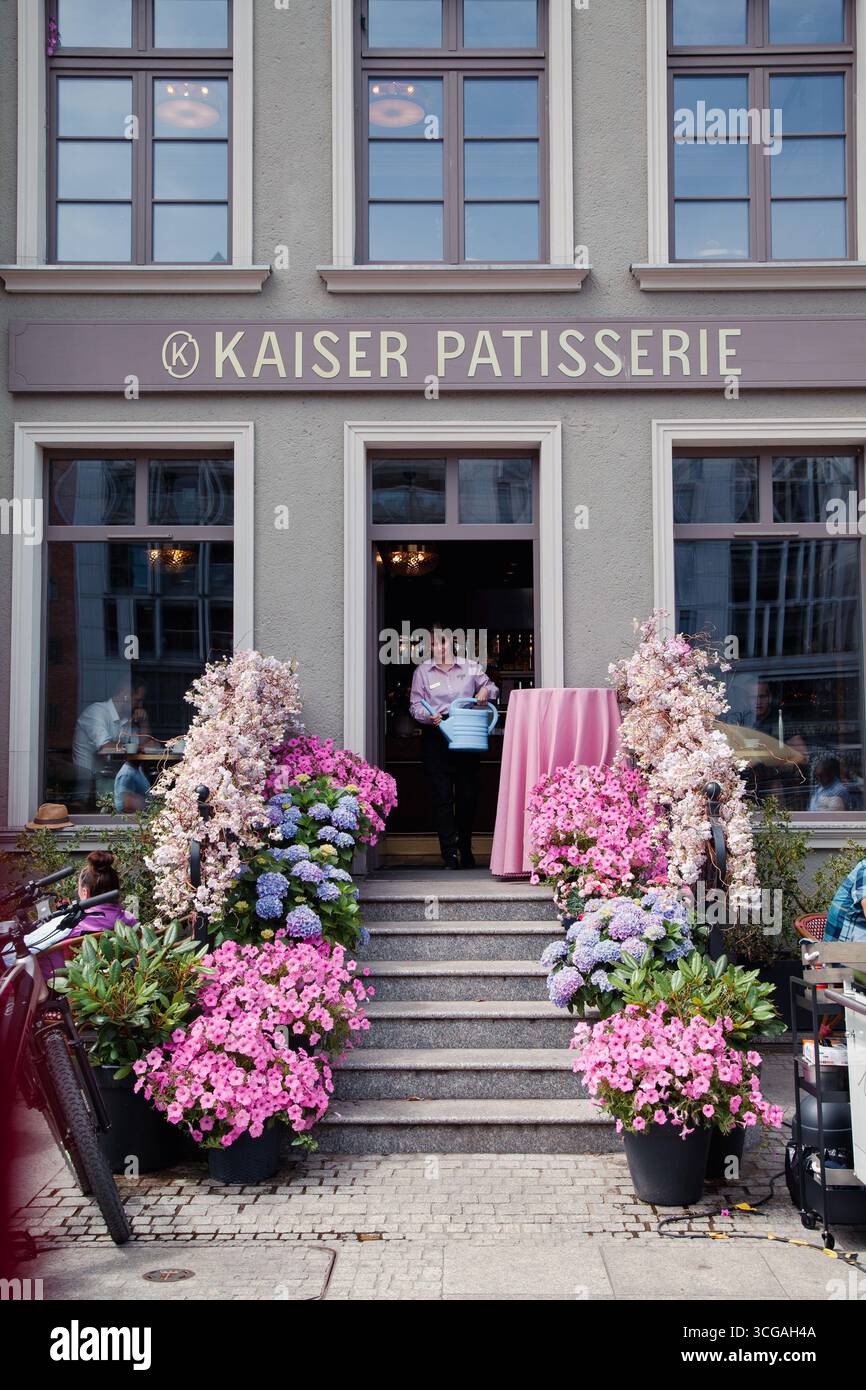 Danzig, Polen - 04-07-2025 - Kaiser Patisserie ist eine Konditorei, Mitarbeiter gehen auf die Veranda und halten eine blaue Dose, um Hortensien zu bewässern Stockfoto