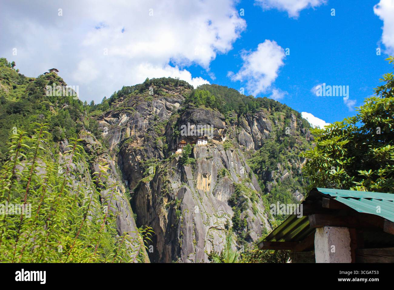 Malerischer Blick auf das Kloster Tiger's Nest in Bhutan, das auf Klippen mit umliegenden Wäldern und Bergen thront, während der Wanderung zu diesem berühmten Wahrzeichen des Himalaya erfasst wird. Stockfoto