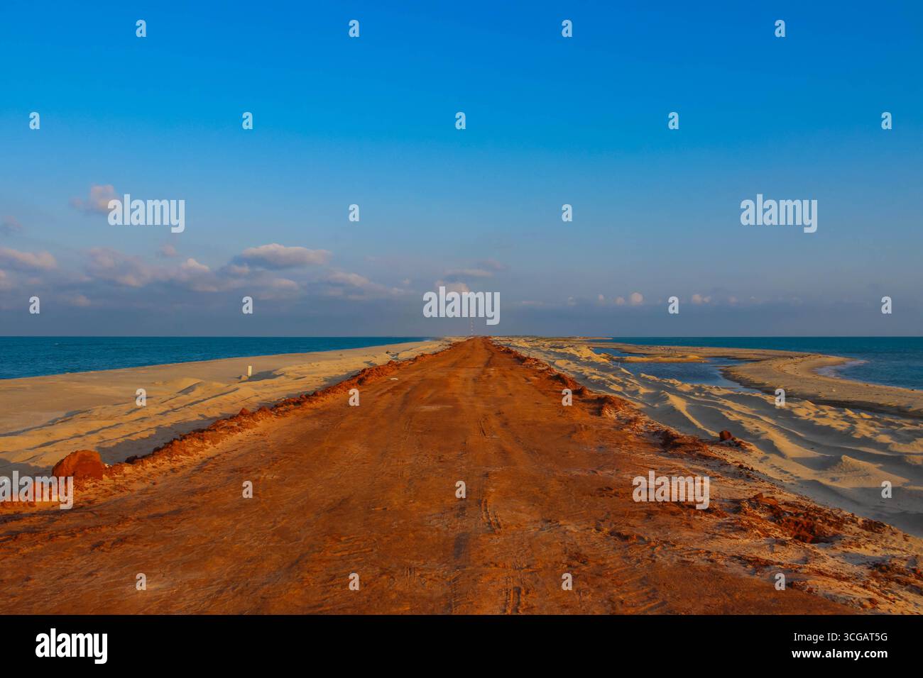 Auf dem Weg nach Dhanuschkodi führt eine enge Straße, die vom Meer flankiert wird, zu den eindringlichen Ruinen der Geisterstadt, die einen atemberaubenden Blick auf das Meer und die Geschichte bietet. Stockfoto