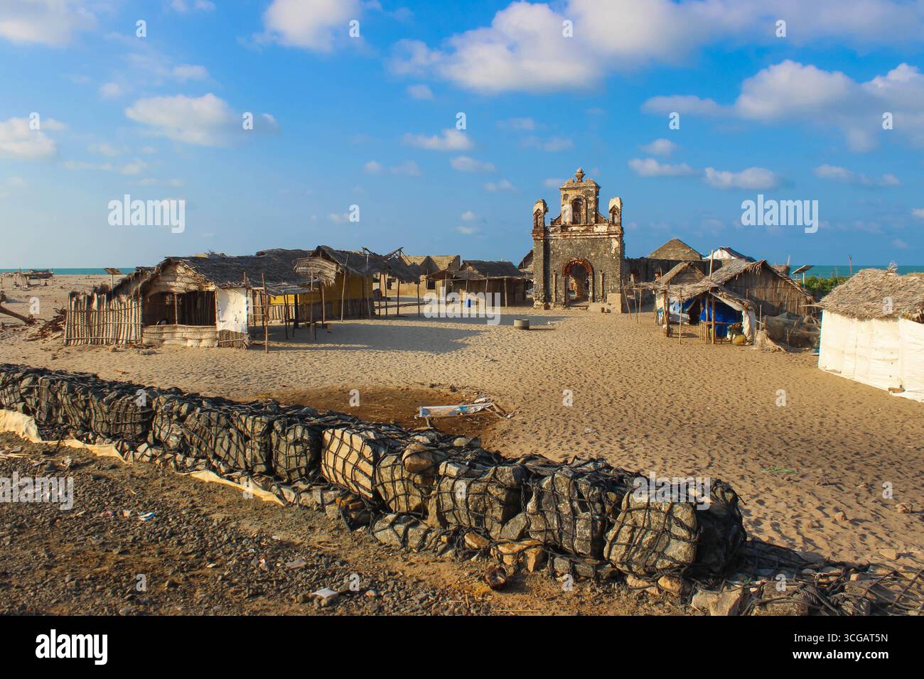 Auf dem Weg nach Dhanuschkodi führt eine enge Straße, die vom Meer flankiert wird, zu den eindringlichen Ruinen der Geisterstadt, die einen atemberaubenden Blick auf das Meer und die Geschichte bietet. Stockfoto